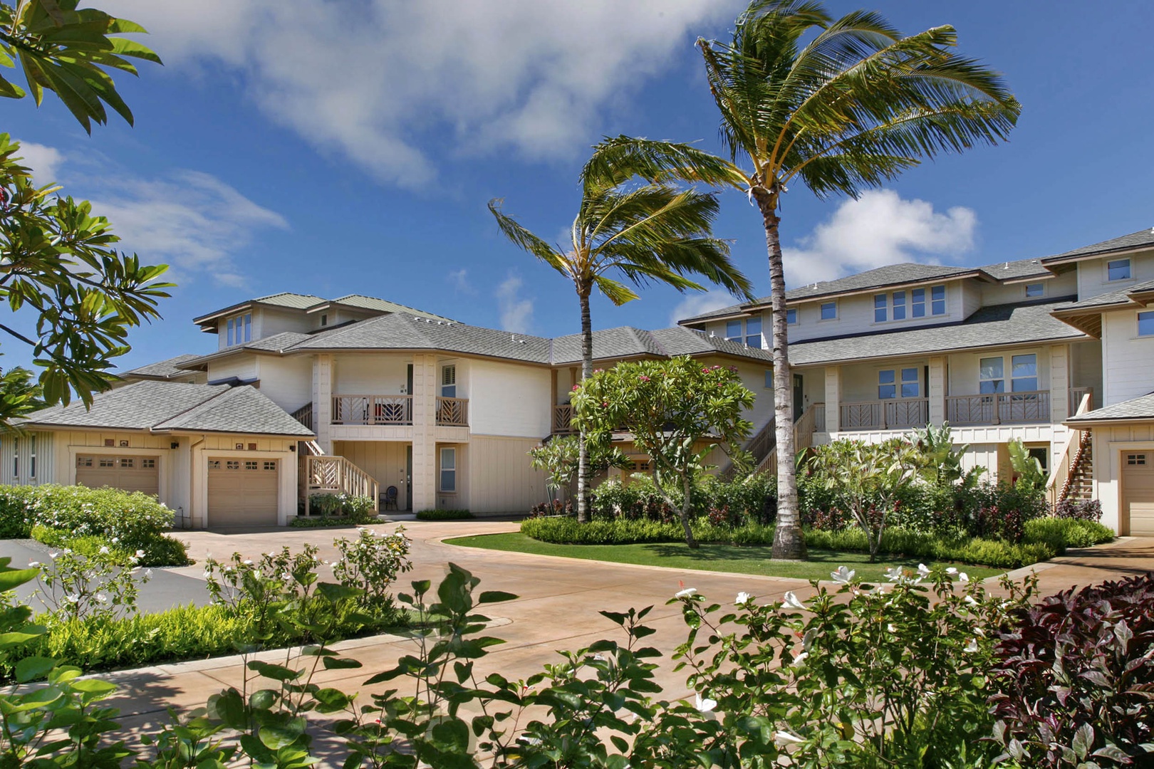 Koloa Vacation Rentals, Pili Mai 6J - Tropical resort buildings surrounded by lush landscaping and swaying palm trees create a serene Hawaiian atmosphere.