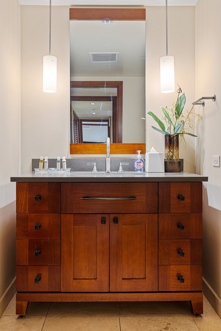 Step into your private bathroom with stylish pendant lighting, elegant wood cabinetry, and thoughtful details—like fresh botanicals and plush amenities waiting for you.