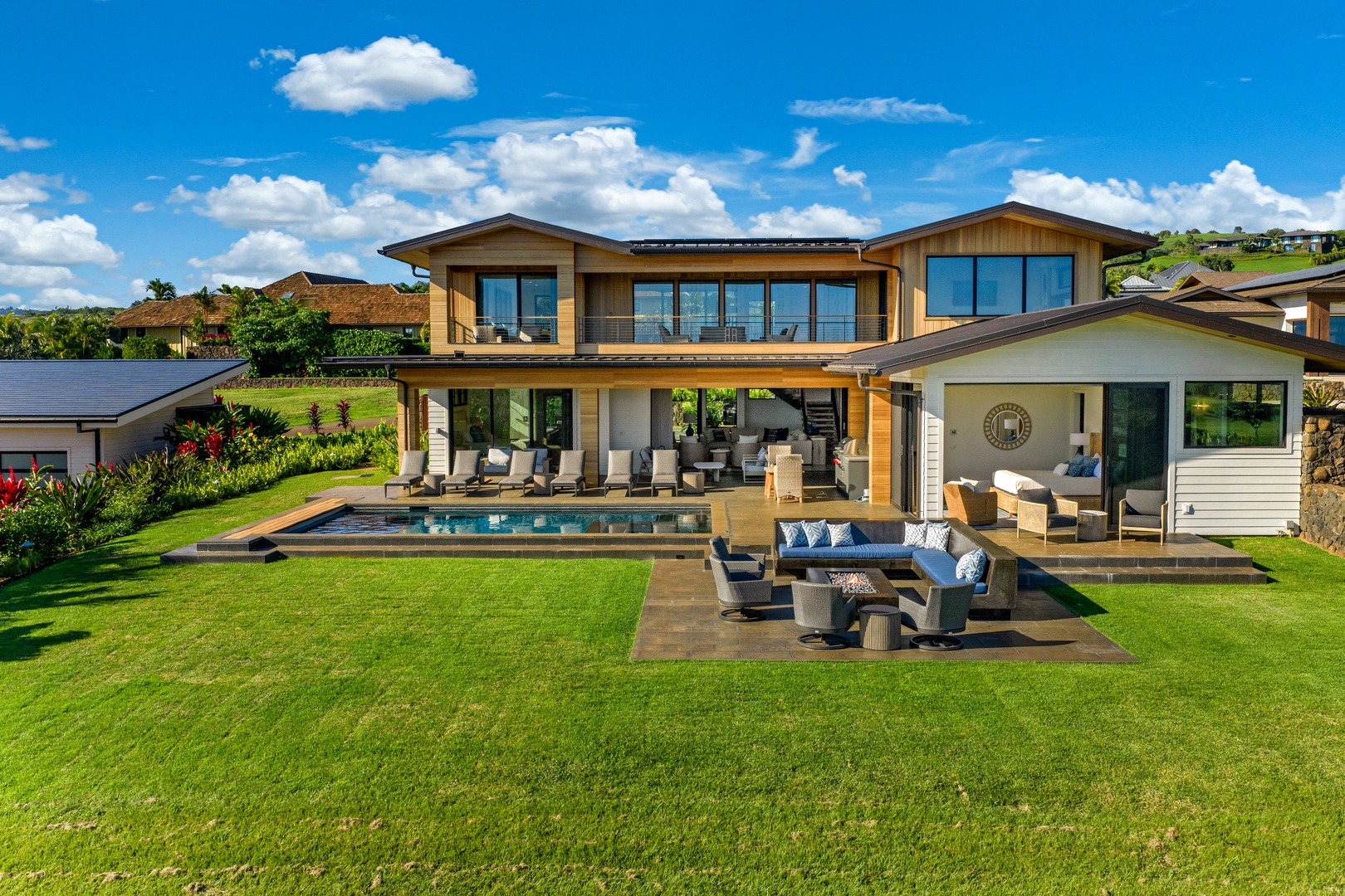 Koloa Vacation Rentals, Hale Laule'a at Kukui'ula - A stunning modern property featuring expansive outdoor living spaces with pool, manicured gardens, and mountain backdrop.