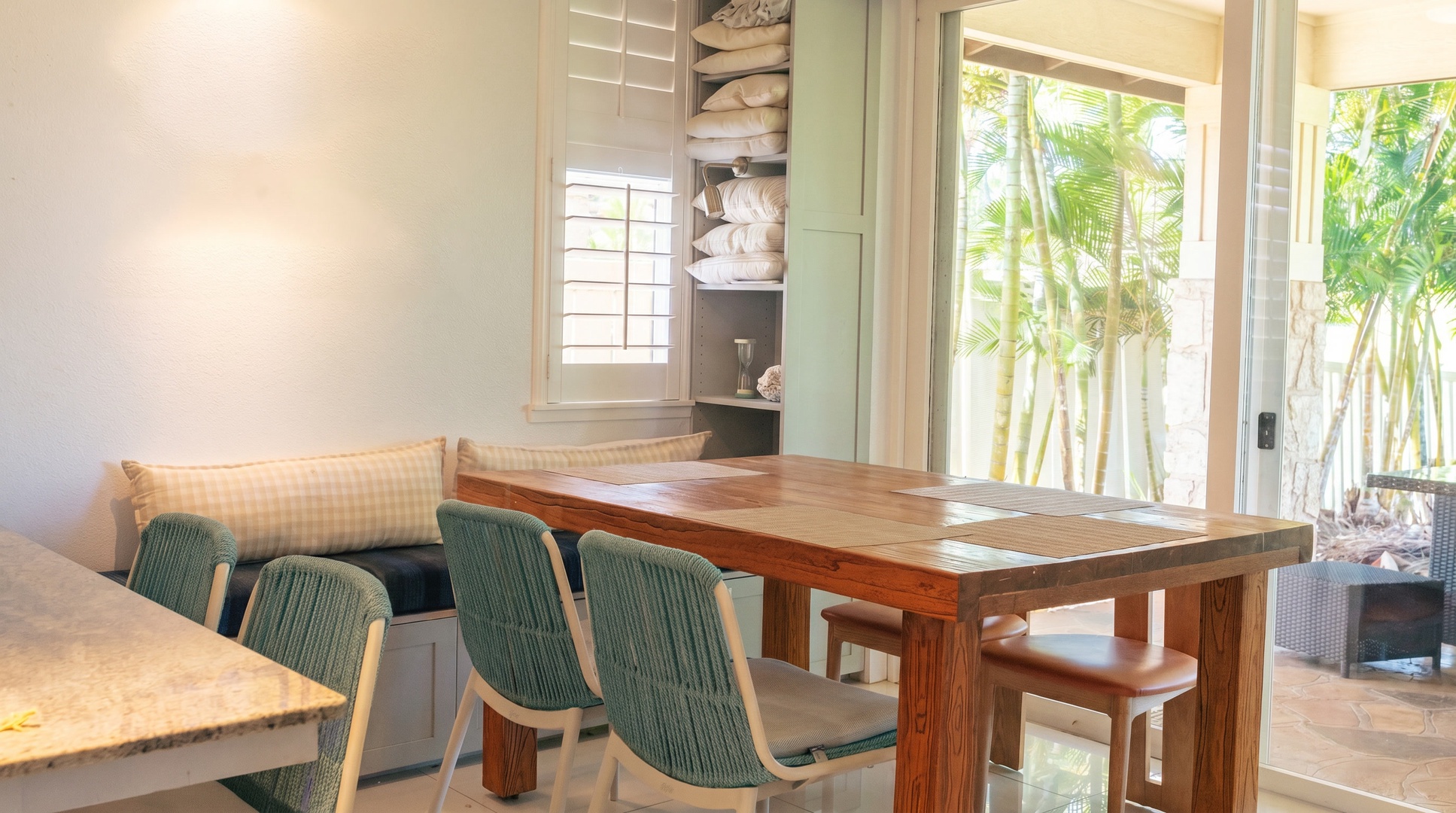 Breakfast at the banquette, with garden light coming through the windows and teal chairs pulled up.