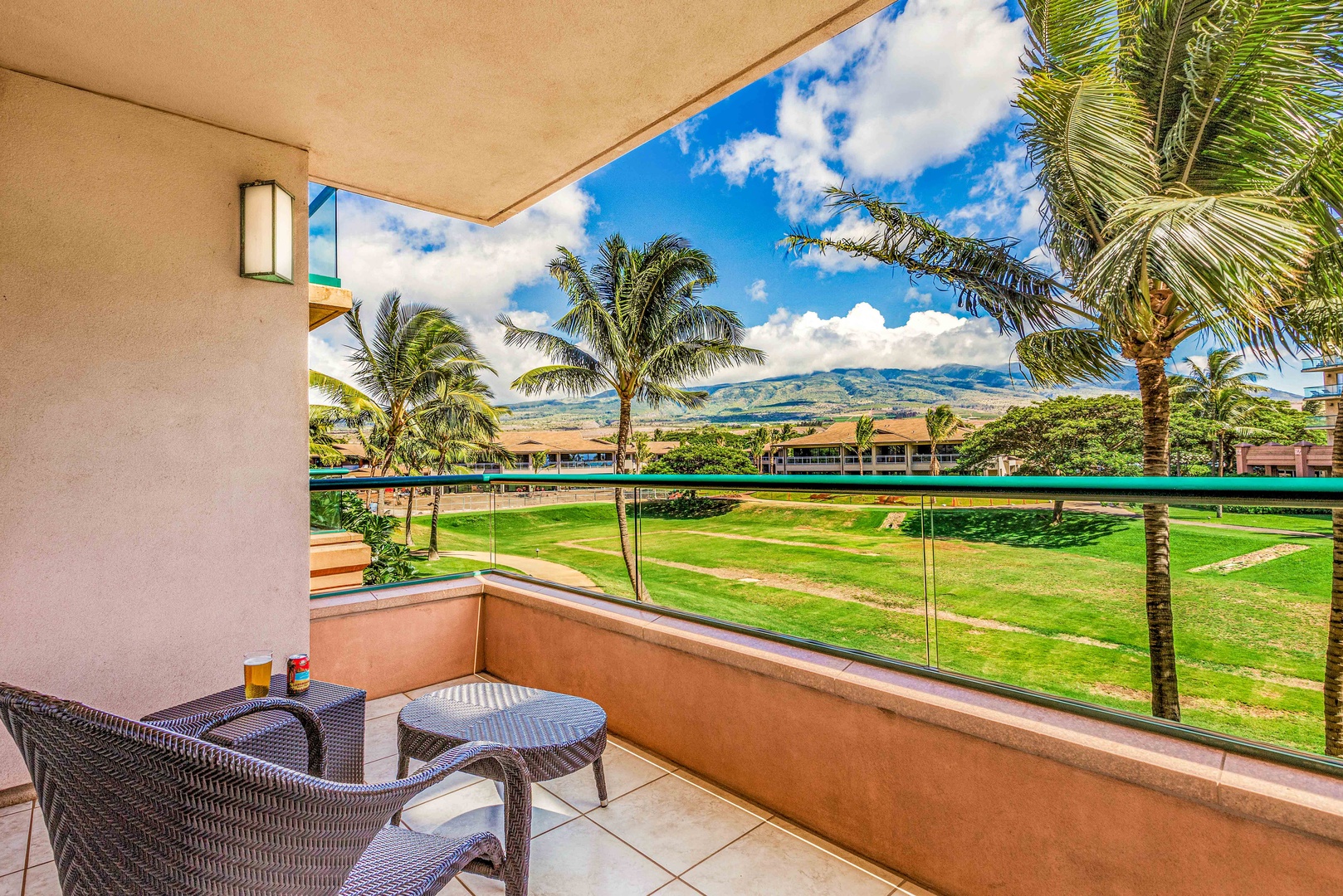 Lahaina Vacation Rentals, Honua Kai Konea 204 - Relax on the lanai with a seating area, overlooking a serene green lawn and offering a scenic view of palm trees and distant mountains