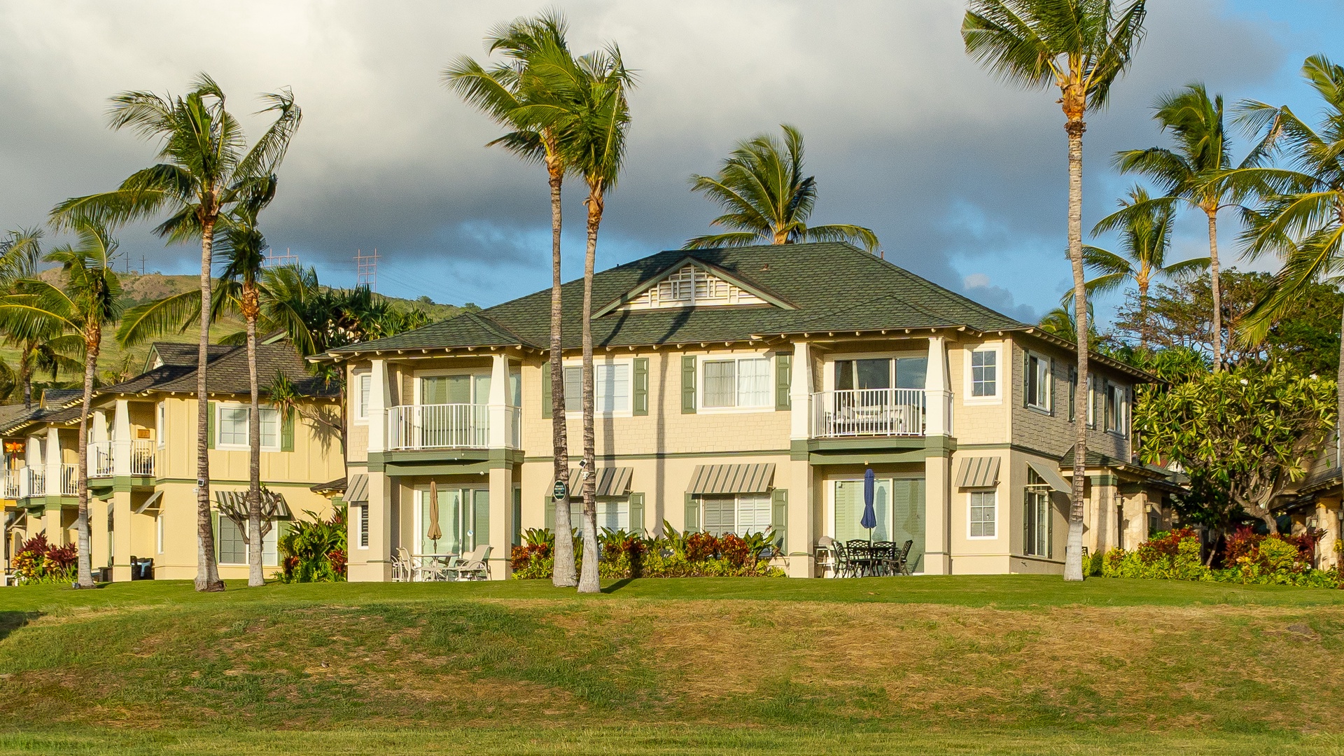 Kapolei Vacation Rentals, Kai Lani 24B - A view of the outside of the condo under swaying palm trees.