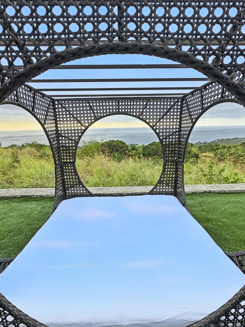 Kailua Kona Vacation Rentals, Hale Nai'a - Garden daybed set beneath a sculptural canopy, overlooking rolling greenery and open sky.