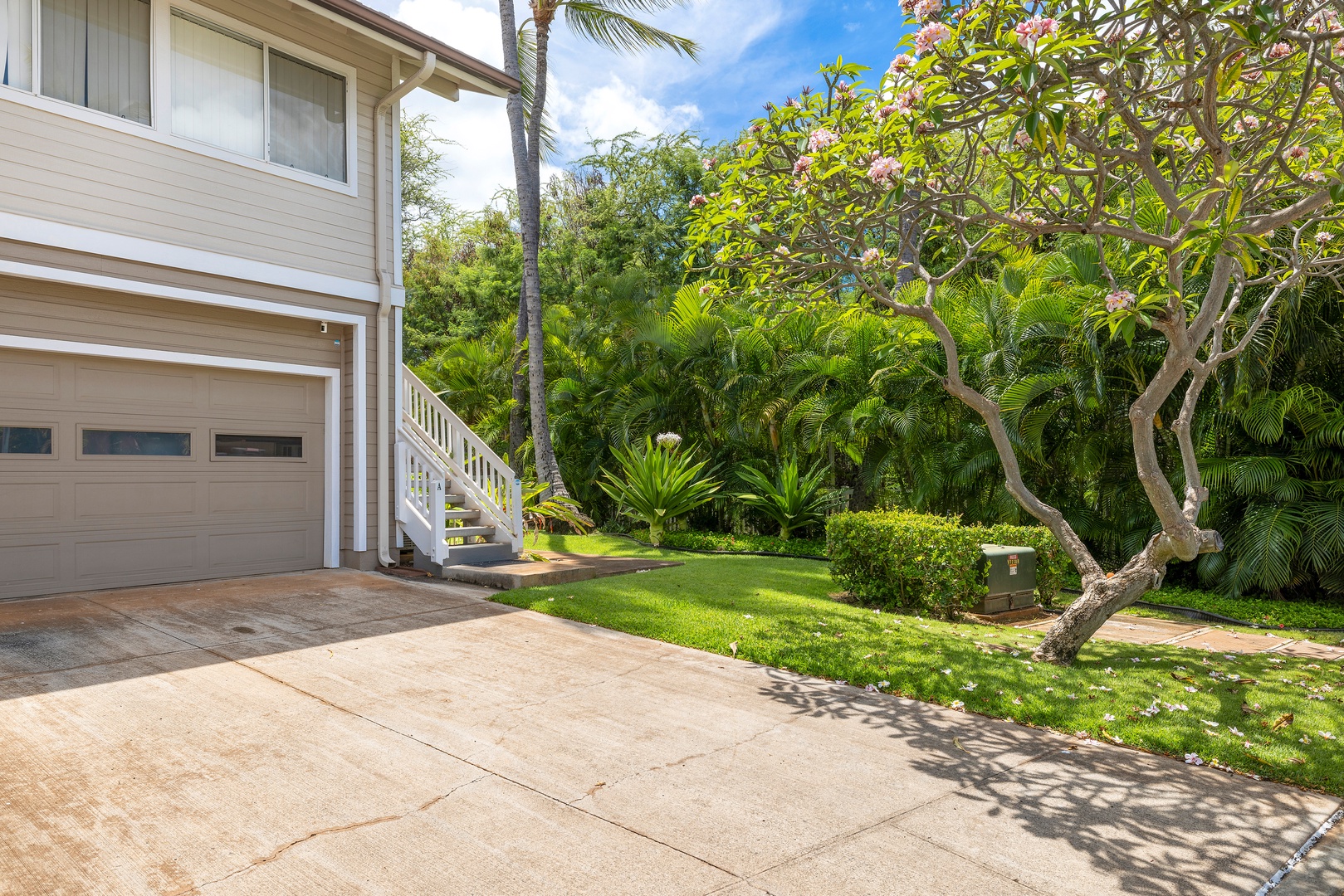 Tropical paradise surrounds this beachside property with lush gardens, swaying palms, and flowering plumeria trees creating a serene Hawaiian escape.