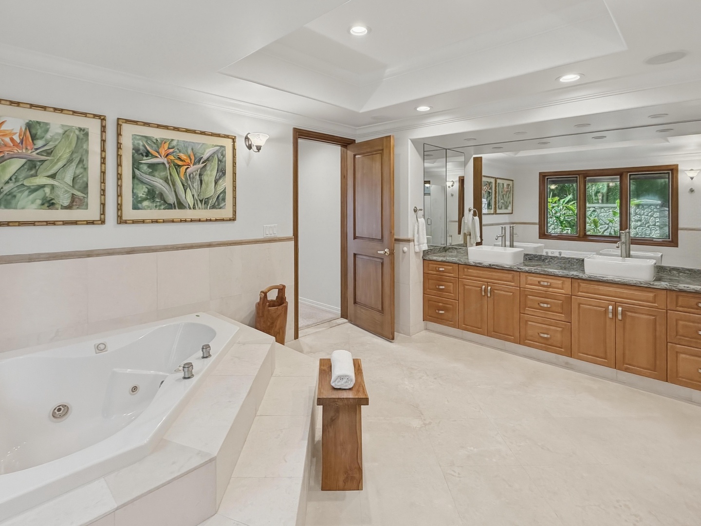 Honolulu Vacation Rentals, Maunalua Estate - Spa-like bathroom retreat with heated marble floors, jetted soaking tub, and dual vanities surrounded by tropical artwork.