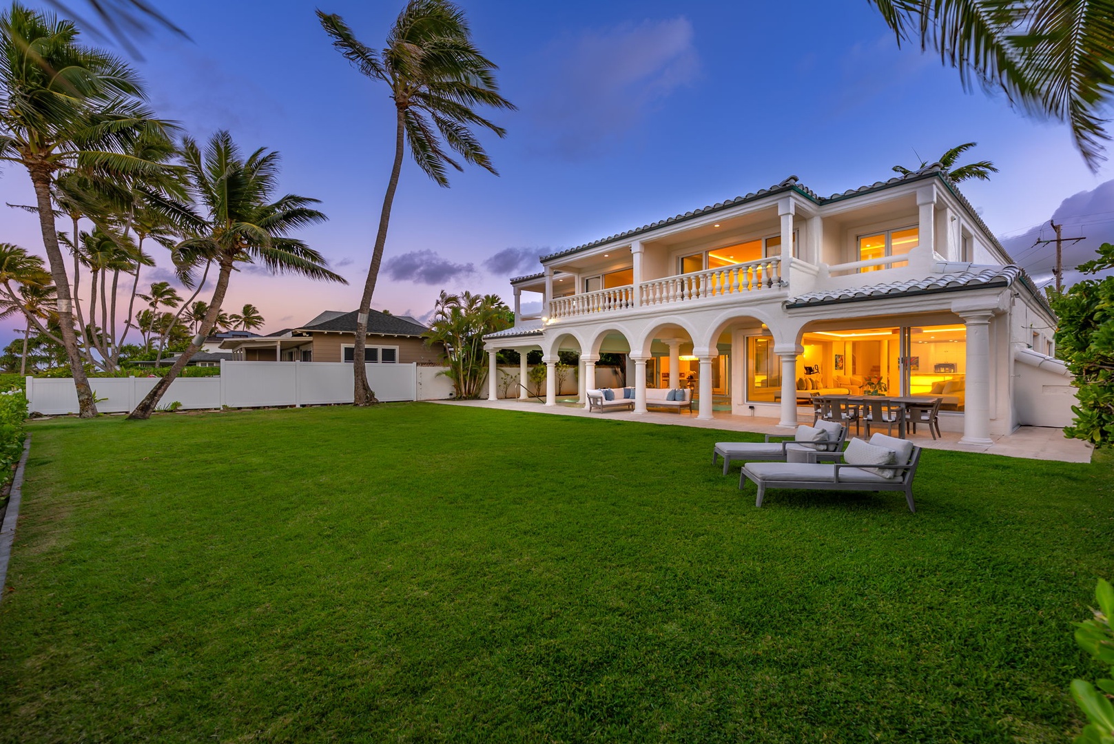 Kailua Vacation Rentals, Lanikai Sunrise Estate - As twilight sets in, the lush green lawn and estate's elegant arches glow with warmth and island charm.