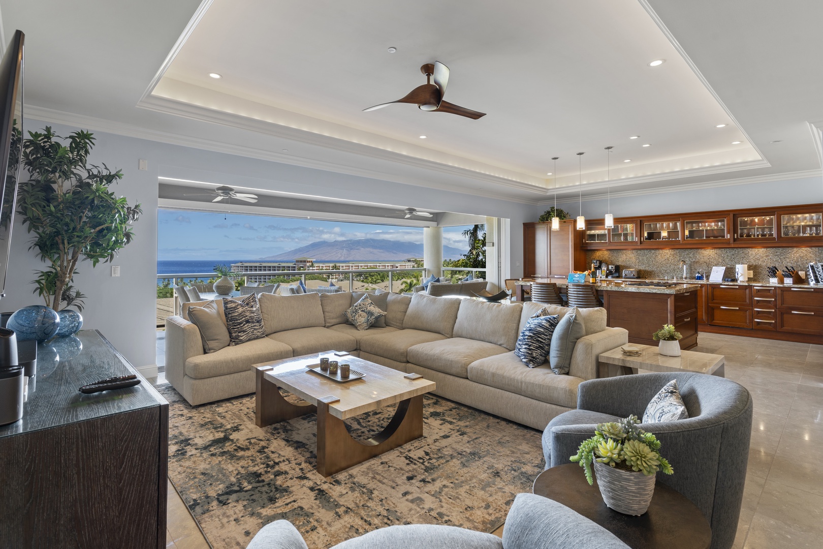 Wailea Vacation Rentals, Wailea Luxury Residence Hoolei 23-3 - The open-concept living area blends modern luxury with island charm, offering expansive ocean views through wide sliding doors. The plush sectional sofa and sleek kitchen with high-end appliances create an inviting space.