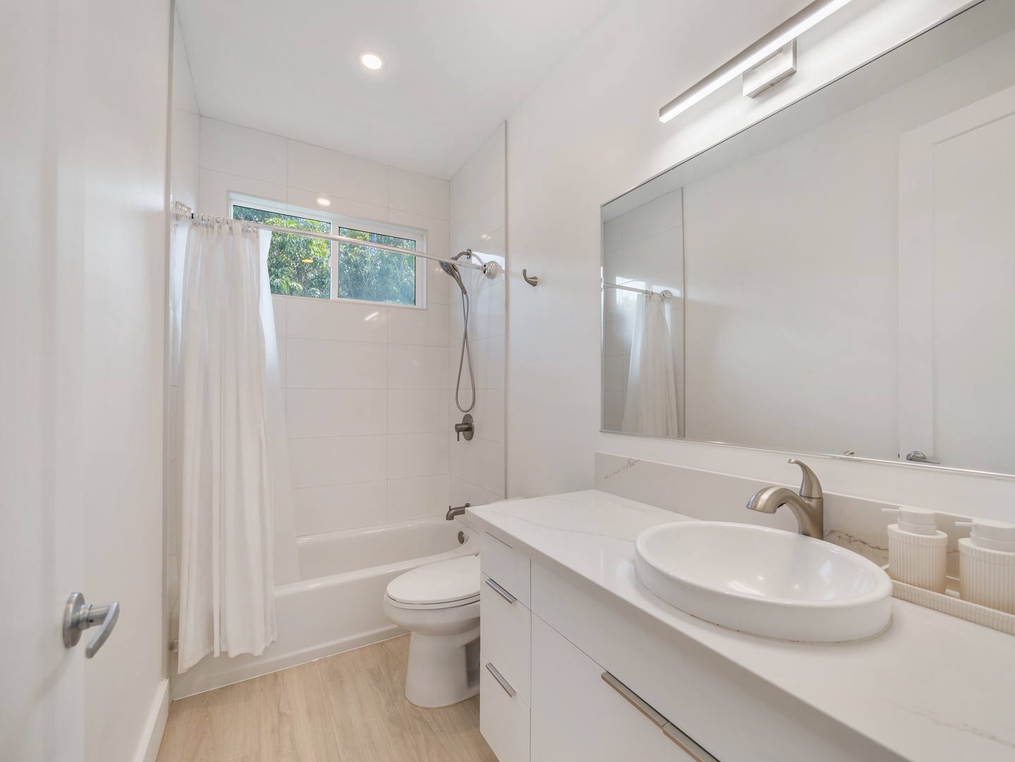 Haleiwa Vacation Rentals, Sunset Beach Island Retreat - The shared bathroom offers a sleek, clean design with a combination shower and tub, a stylish vessel sink, and a large mirror.