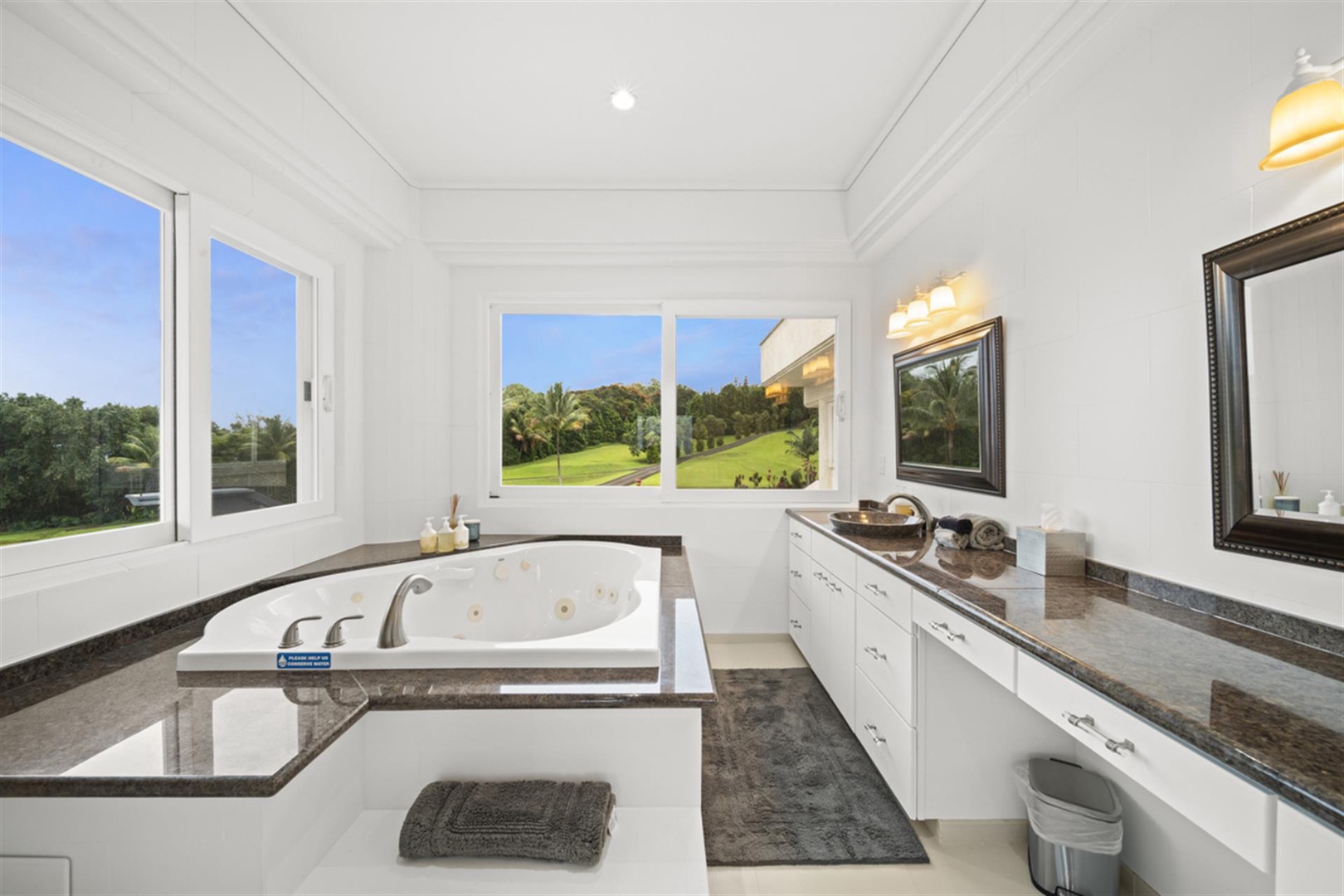 Ninole Vacation Rentals, Waterfalling Estate** - Relax on the ensuite bathroom with a large tub and expansive windows.