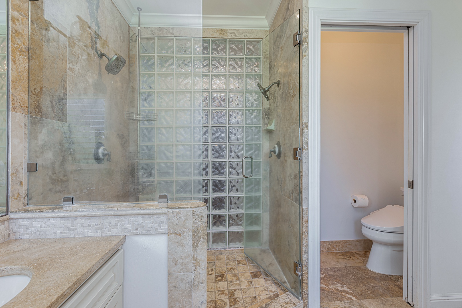 Princeville Vacation Rentals, Ohana Kamalani - Primary ensuite bathroom with walk-in shower and natural stone finishes for a spa-like experience.