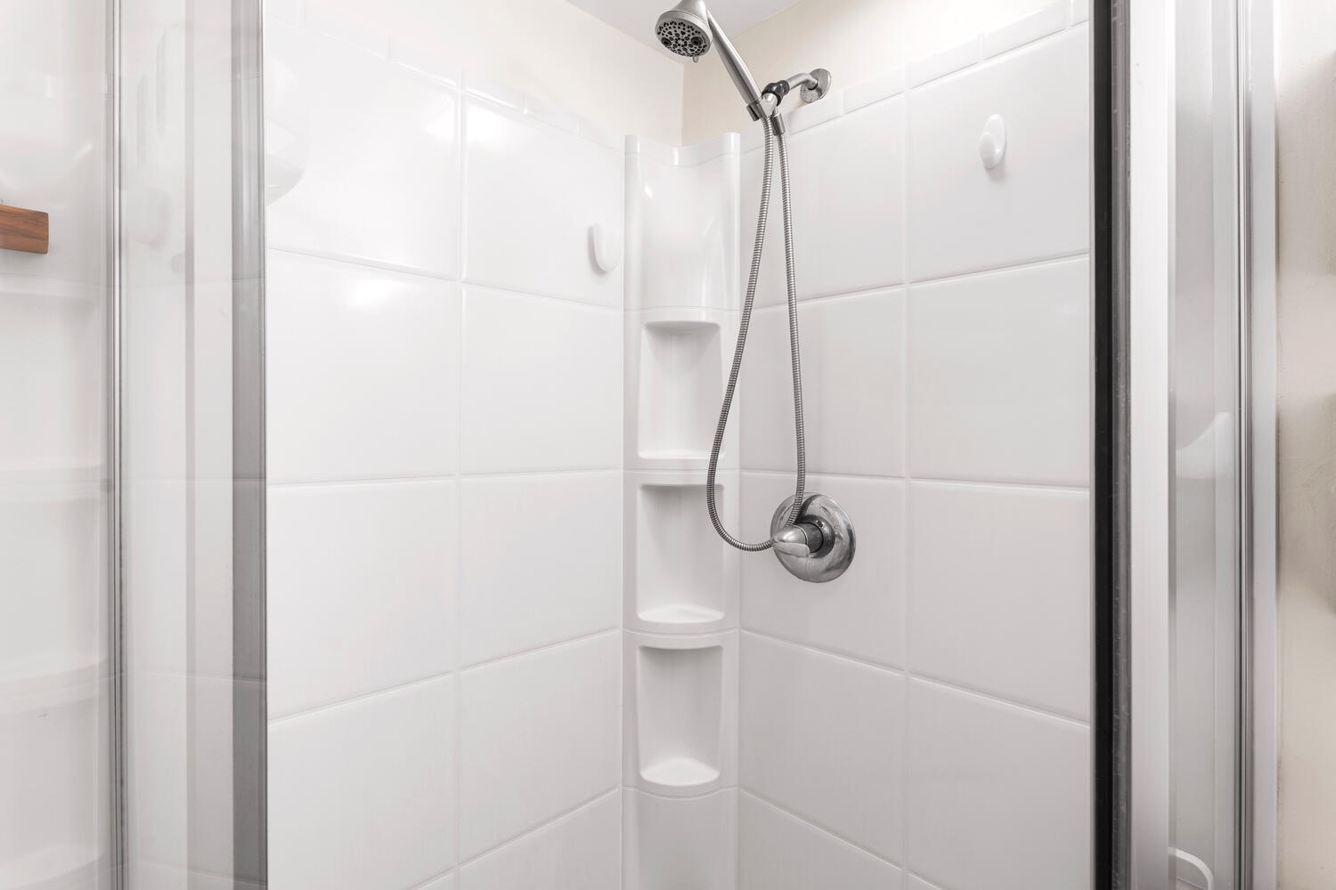 Kailua Kona Vacation Rentals, Kona Plaza 201 - Step into your pristine white-tiled shower with modern fixtures and built-in corner shelving for your essentials.