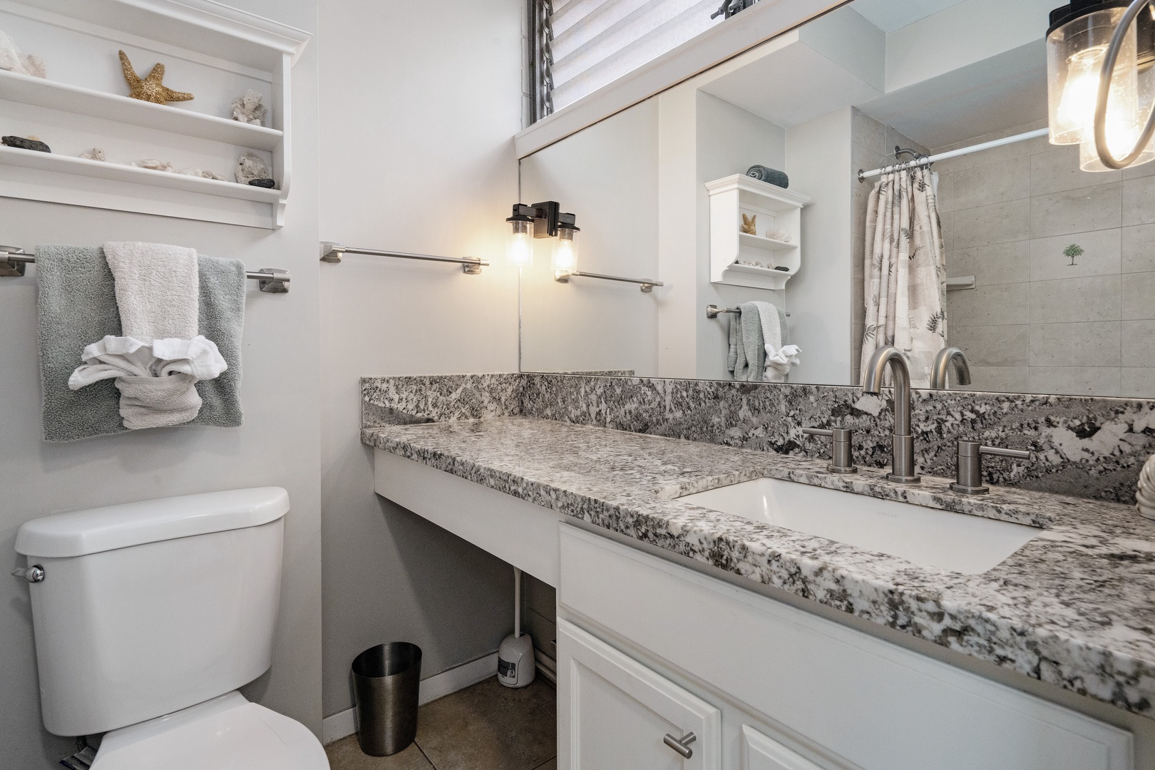 Kihei Vacation Rentals, Haleakala Shores A206 - Get ready for dinner at a granite vanity lit by warm sconces, with starfish and coral on the shelf above.