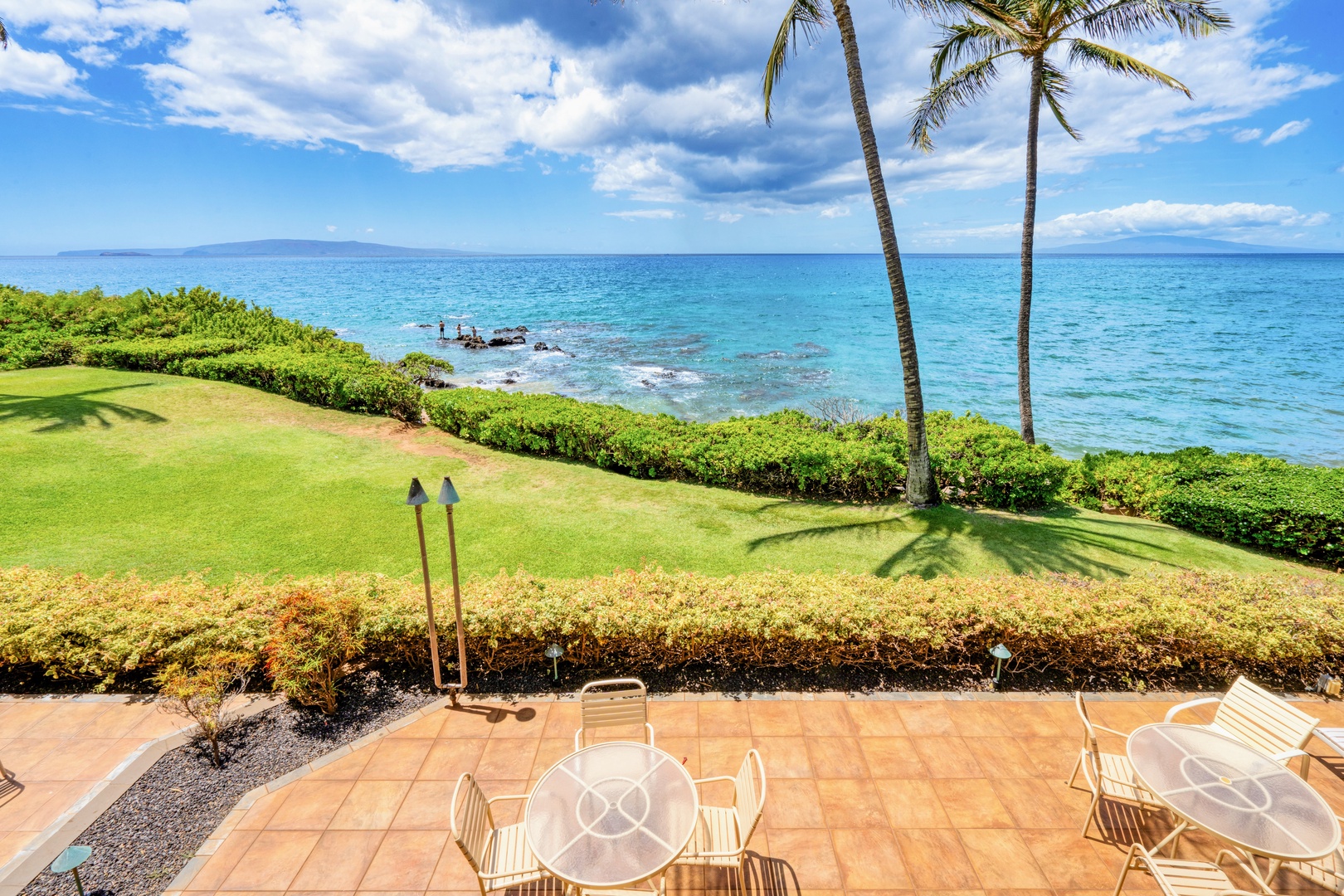 Kihei Vacation Rentals, Punahoa Beach 205 - Pull out a patio chair and watch the waves roll onto the rocks just past the palms.