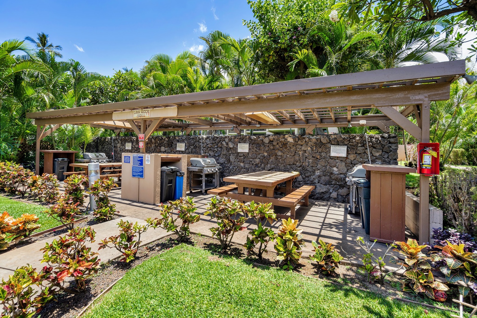 Kihei Vacation Rentals, Kamaole Sands 5310 - Fire up a grill at the Lava Rock Grill pavilion, picnic tables set against a lava rock wall.