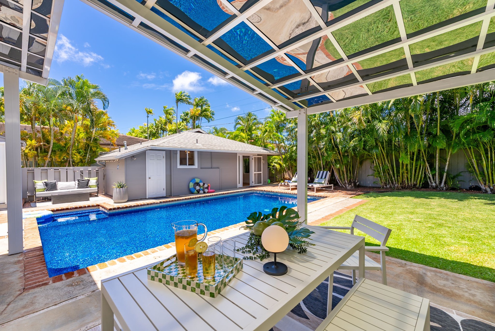 Honolulu Vacation Rentals, Ho'okipa Villa - Tropical retreat featuring a sparkling pool framed by lush palms, a spacious lawn, and a covered patio with comfortable seating—your perfect space to relax, refresh, and soak up the Florida sunshine.