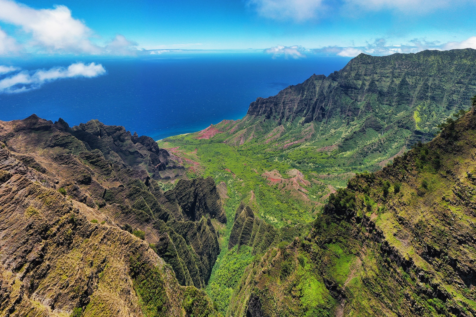 Koloa Vacation Rentals, Ke Kai Nui at Kukuiula - Stunning aerial view of Kalalau Valley, showcasing rugged cliffs, lush landscapes, and the Pacific Ocean.