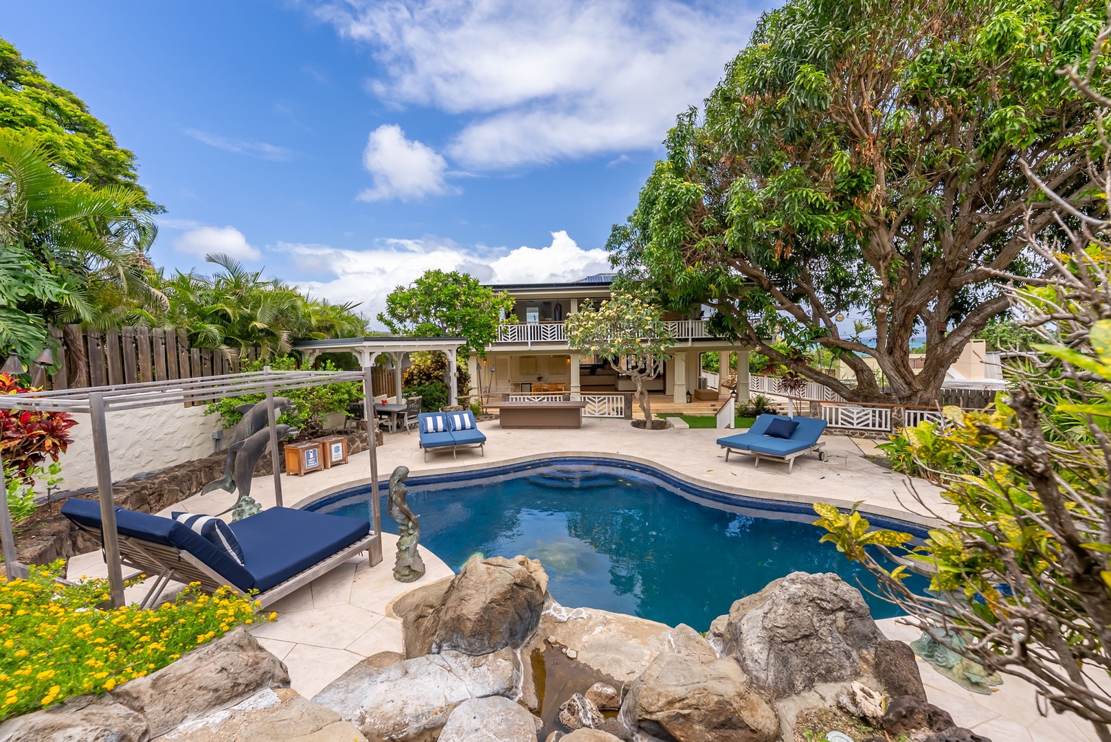 Kailua Vacation Rentals, Leaf House - Tropical paradise awaits with a sparkling pool framed by lush palms and natural rock features, sunbeds ready for lazy afternoon escapes beneath azure skies.
