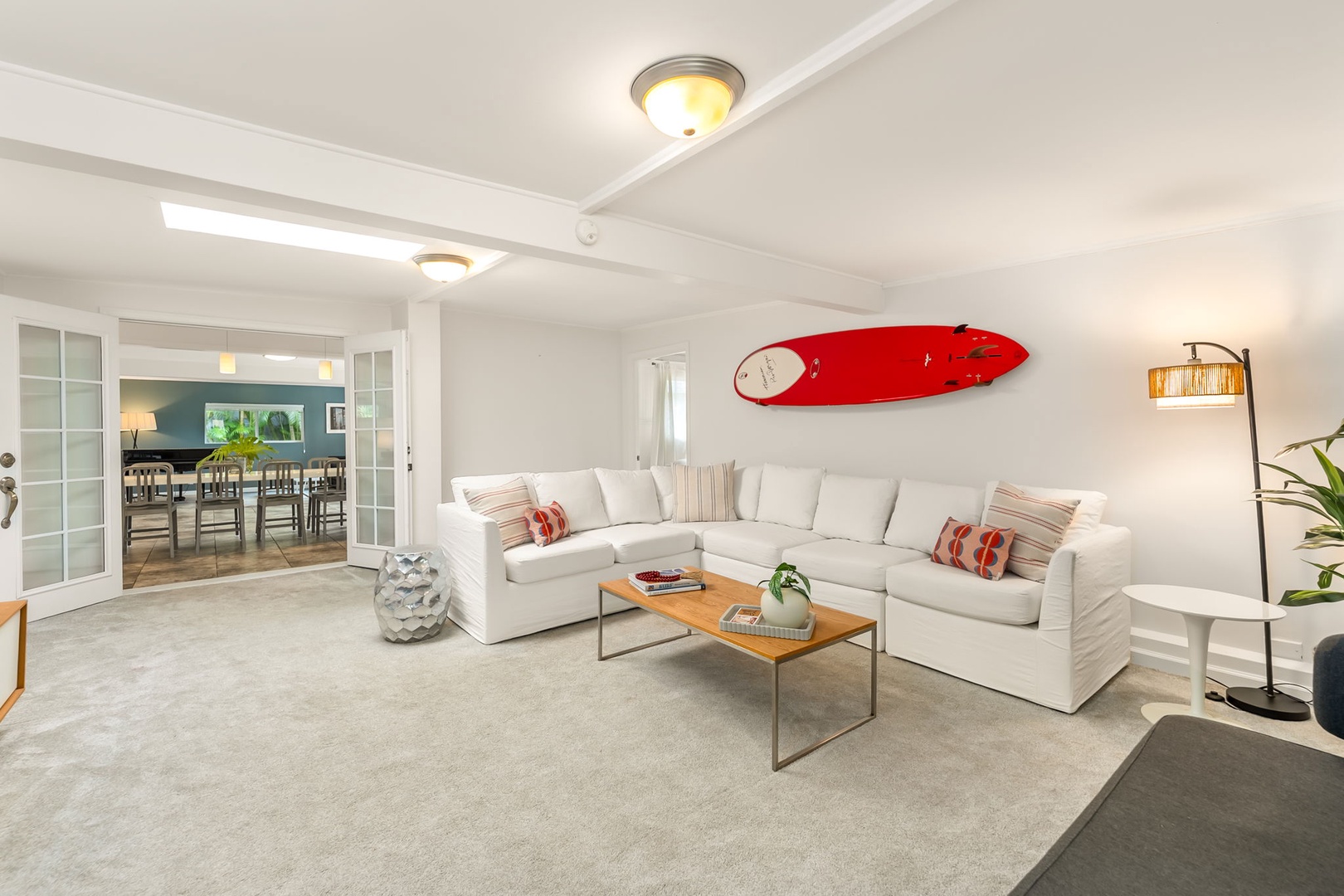 Honolulu Vacation Rentals, Ho'okipa Villa - Unwind on plush sofas in your bright living room, where a bold red surfboard hints at nearby beach adventures and cozy evenings await by soft lamplight.