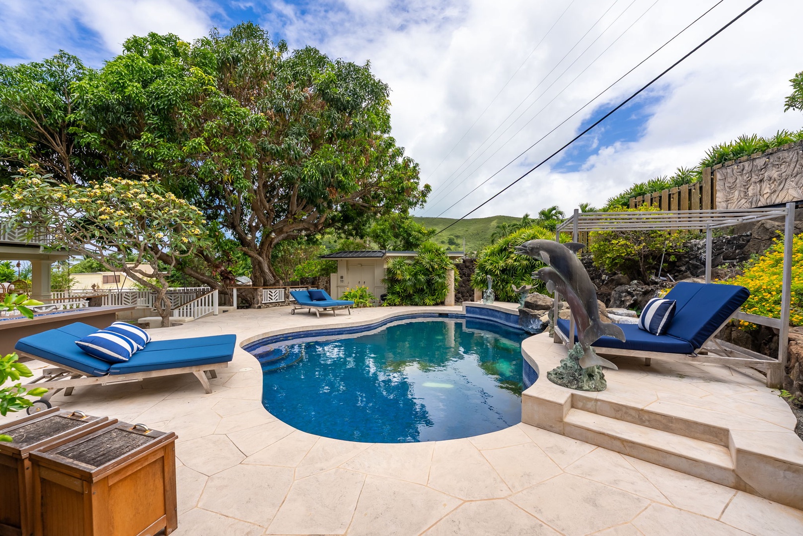 Kailua Vacation Rentals, Leaf House - Private pool with dolphin fountain, blue loungers, lush tropical trees, and mountain backdrop—your sunny Hawaiian oasis awaits beneath clear island skies.