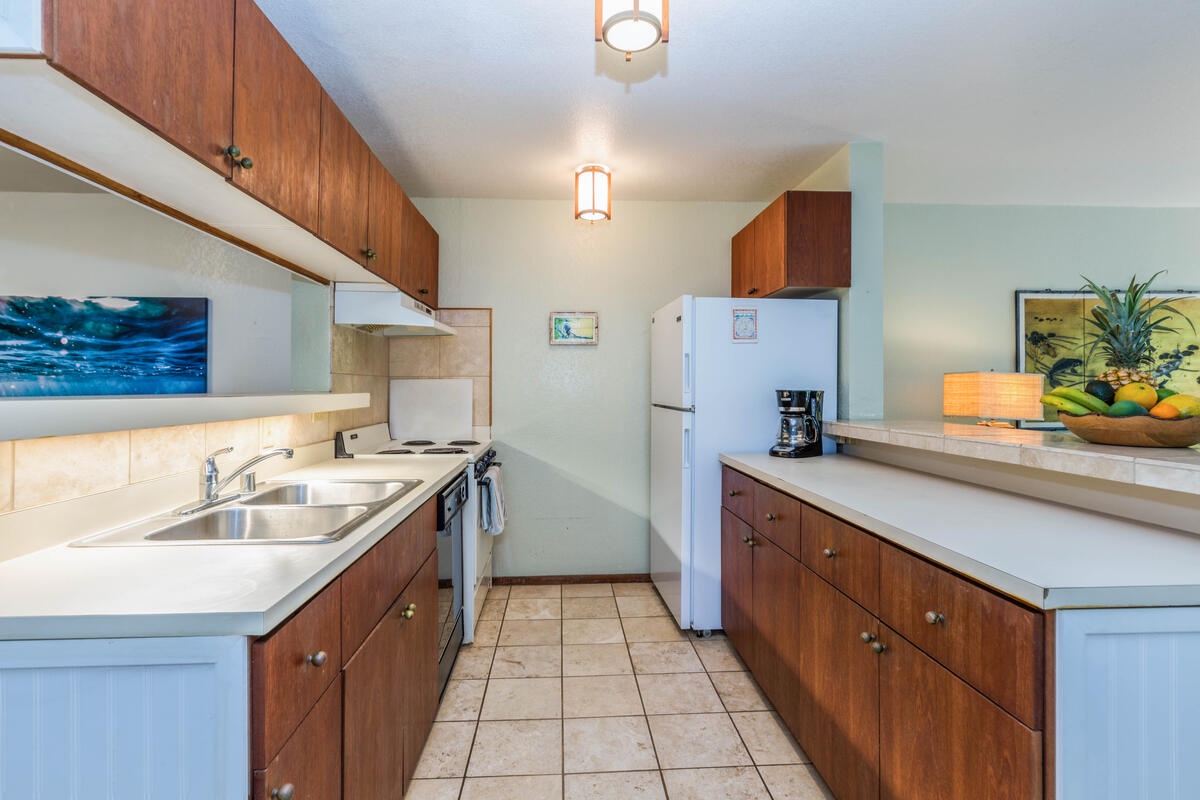 Koloa Vacation Rentals, Waikomo Streams 121 - The kitchen pass-through offers some separation, while also keeping open sightlines to the rest of the space, and the greenery that lies beyond.