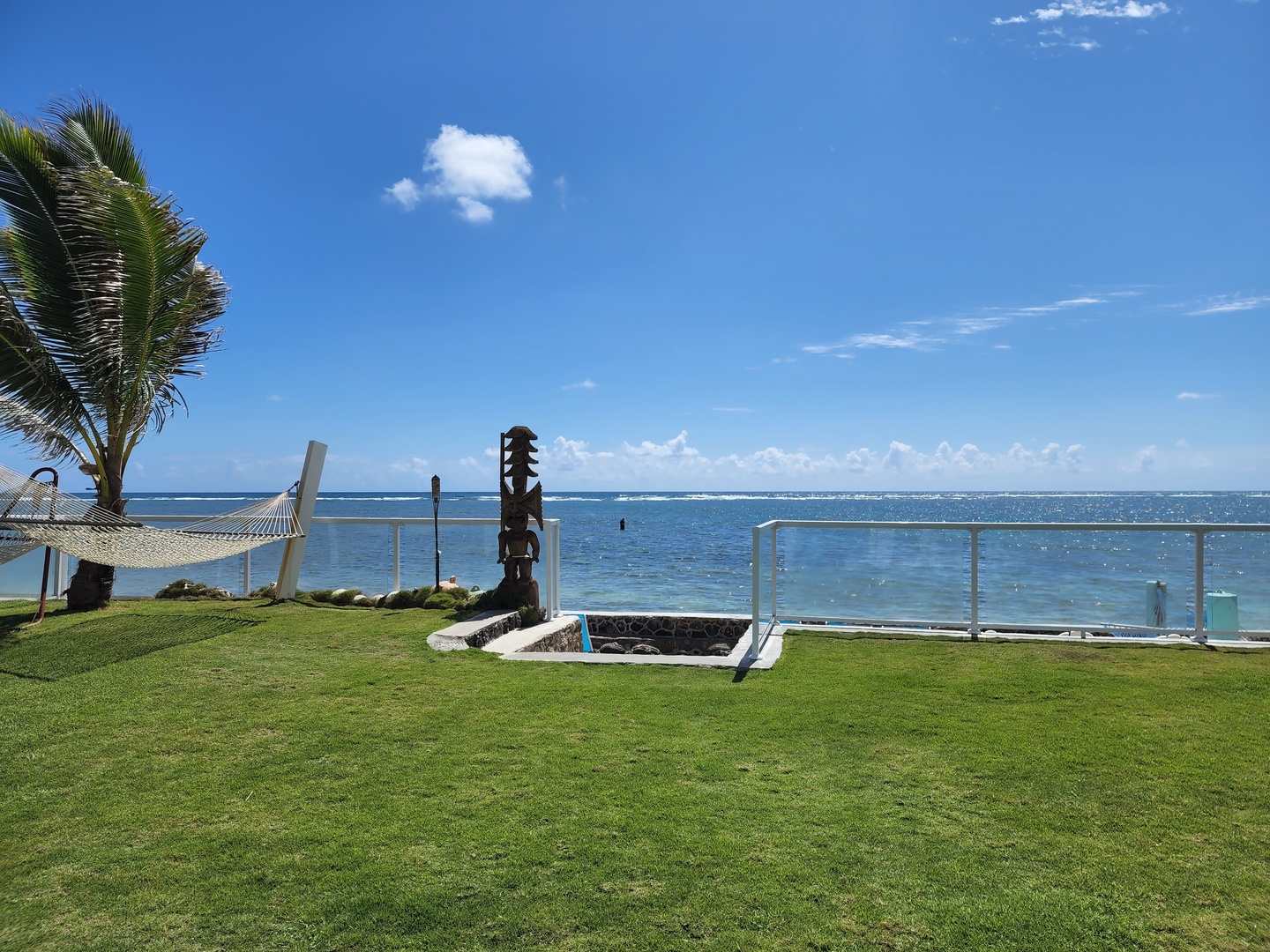 Hauula Vacation Rentals, Private Beach Paradise - Open lawn running to the shoreline, a tiki marking where it meets the sea.