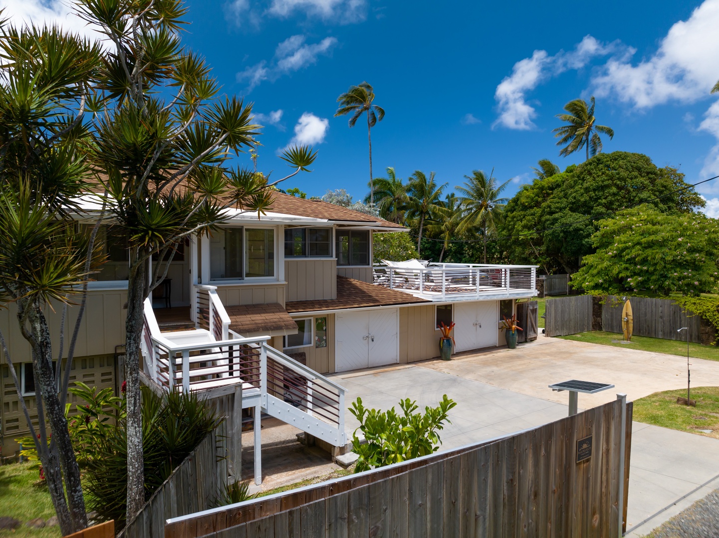 Kahuku Vacation Rentals, Hale Pellicano - The exterior of the home features a spacious upper deck and private yard, perfect for outdoor dining and enjoying the tropical surroundings.