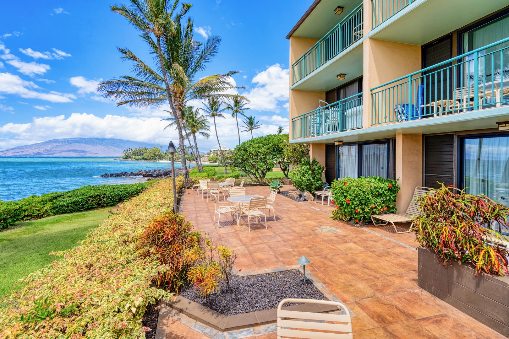 Kihei Vacation Rentals, Punahoa Beach 205 - Teal balconies stack above a shared lanai, with mountains rising across the water beyond.