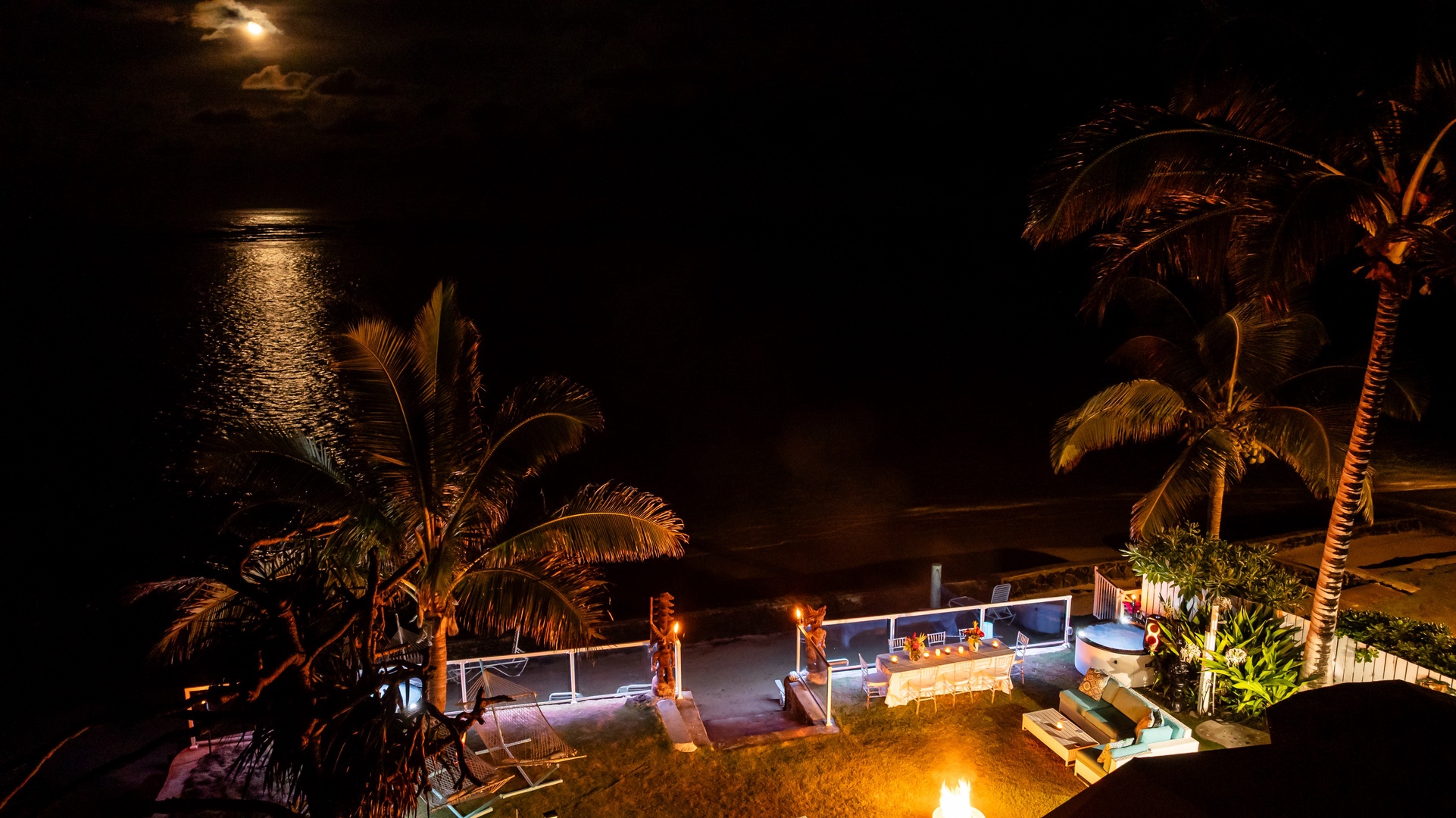 Hauula Vacation Rentals, Private Beach Paradise - Moonlit beachfront setting with glowing lounge areas, swaying palms, and a cozy fire pit.
