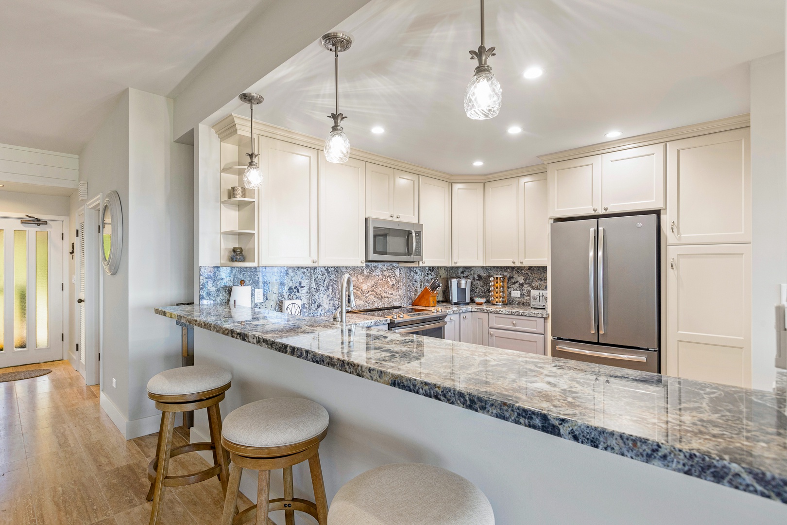 Lahaina Vacation Rentals, Kapalua Ridge 1622 - This spacious kitchen boasts elegant granite countertops and a breakfast bar with seating for three, illuminated by stylish pendant lighting.