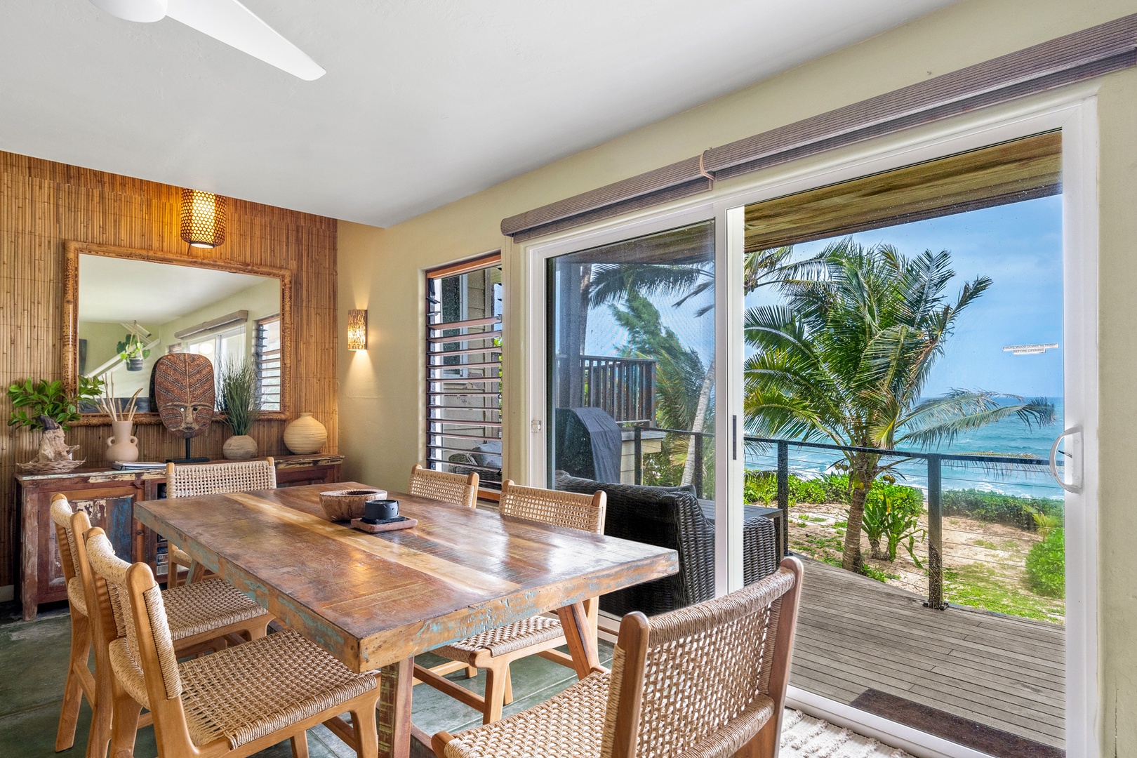 Hanalei Vacation Rentals, Hale Kepuhi - The tropical dining room frames stunning ocean views through floor-to-ceiling windows, where palm trees sway just beyond your private terrace.