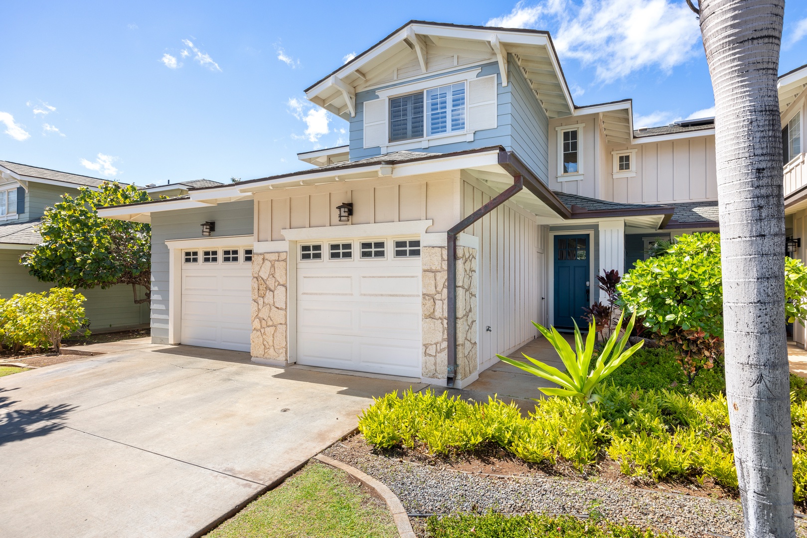 Modern coastal home with tropical landscaping and convenient garage parking in a peaceful residential setting.