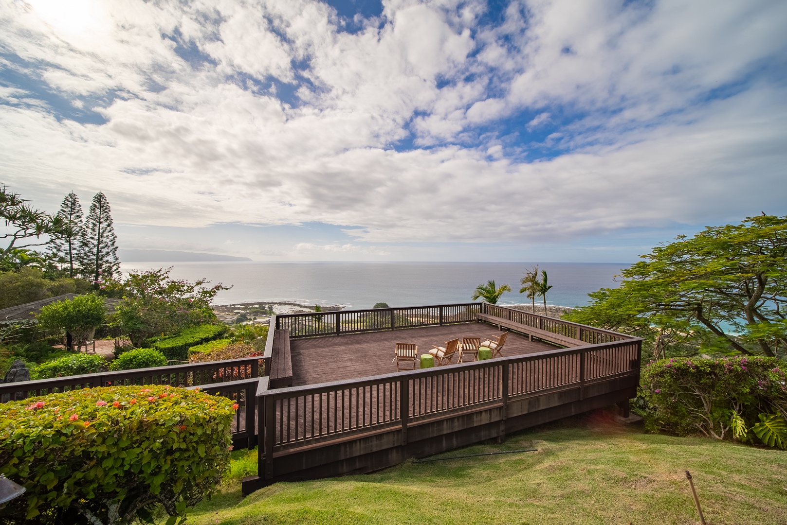 Haleiwa Vacation Rentals, Ka Hale Hau'oli - Elevated wooden deck with panoramic ocean views, surrounded by lush tropical gardens and open sky.