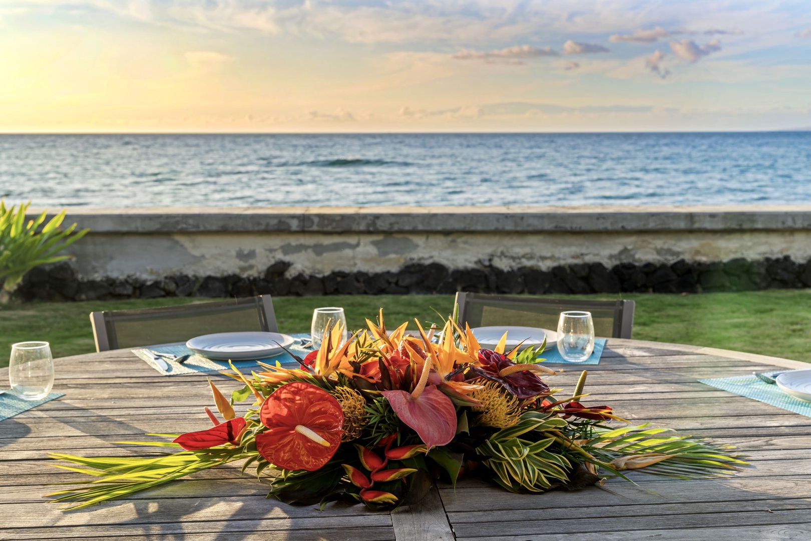 Kamuela Vacation Rentals, Island Time Retreat - A tropical centerpiece and a set table, ocean glinting behind the chairs.