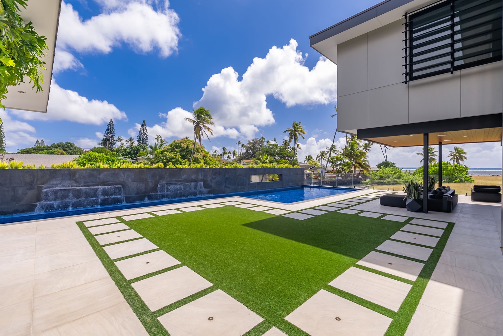 Honolulu Vacation Rentals, Ocean Villa 3 Bedroom - Manicured lawn and pool area set against swaying palms and open sky.