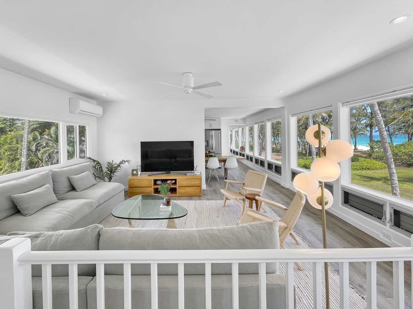 Waimanalo Vacation Rentals, Hale Waimanalo - The oversized gray sectional and woven accent chairs in the living room are positioned in front of a large flatscreen TV, but the real show is happening outside the expansive windows, where you have unobstructed beach and ocean views