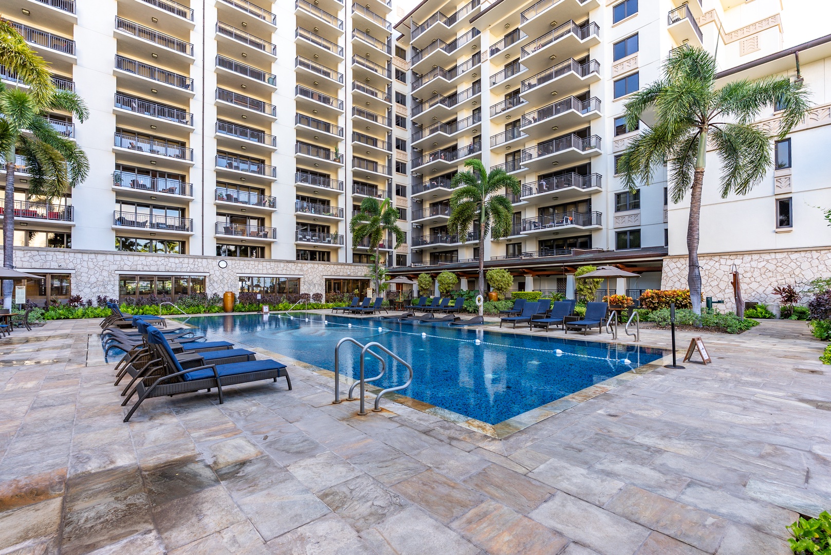 Long pool, loungers down one side, a villa tower rising behind.