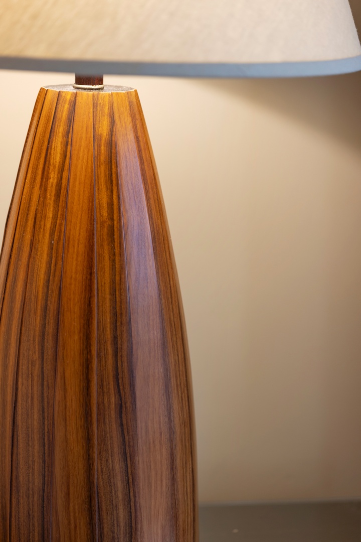A warm wooden lamp base with natural grain details creates soft ambient lighting to enhance your relaxation in the space.