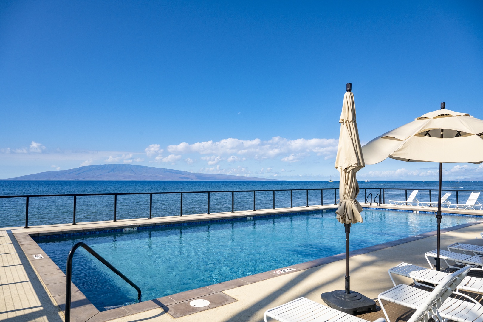 Lahaina Vacation Rentals, Puamana 240-3 - Sun loungers and umbrellas line the pool deck, offering the ultimate in beachfront comfort.