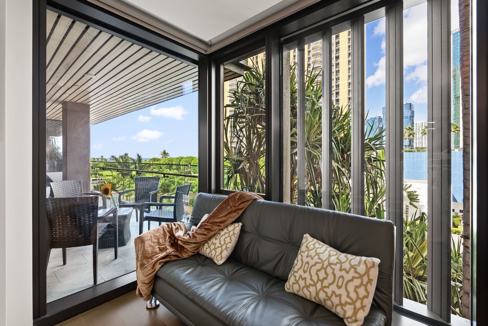 Honolulu Vacation Rentals, Park Lane Getaway - Cozy indoor seating area with a view of the balcony and lush surroundings, ideal for relaxing with a good book.