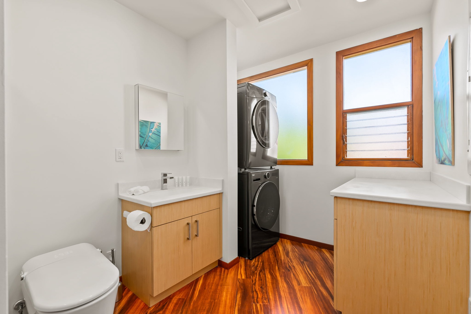 Honolulu Vacation Rentals, Black Point Ocean Villa - An accessible half bathroom doubles as a laundry space combining convenience with style, featuring modern appliances and natural light from warm wood-framed windows.