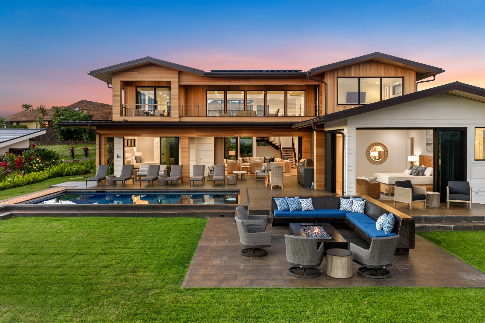 Koloa Vacation Rentals, Hale Laule'a at Kukui'ula - Modern luxury home featuring premium outdoor entertaining spaces with swimming pool, hot tub, elegant fire pit seating, and contemporary architecture at twilight.