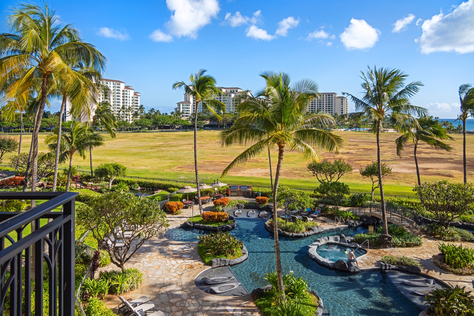 Kapolei Vacation Rentals, Ko Olina Beach Villas B403 - Stunning resort pool surrounded by swaying palms and golf course views under tropical blue skies.