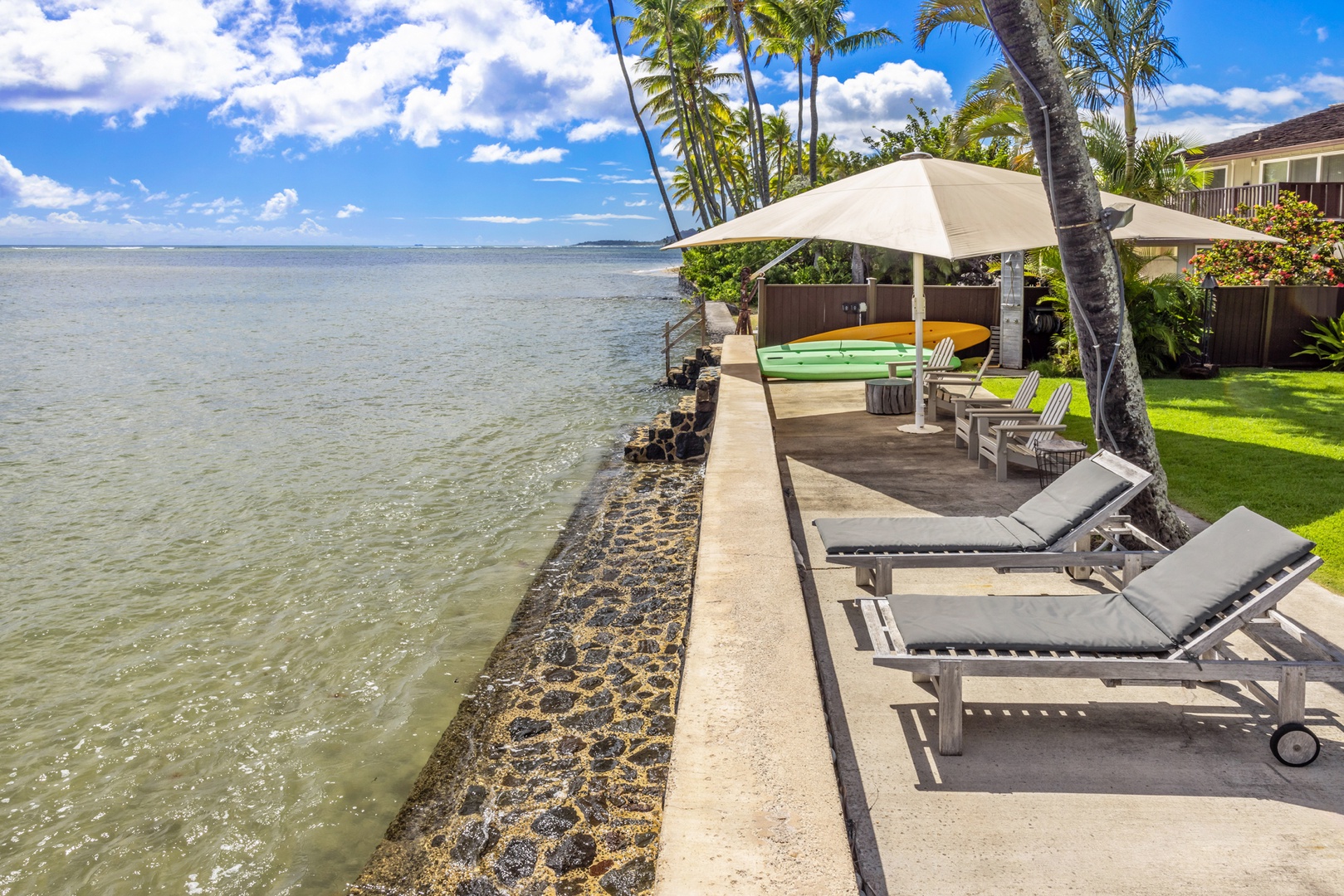 Honolulu Vacation Rentals, Moana Lani - Main House - Stretch out on a lounger along the seawall, with clear, shallow water right below.