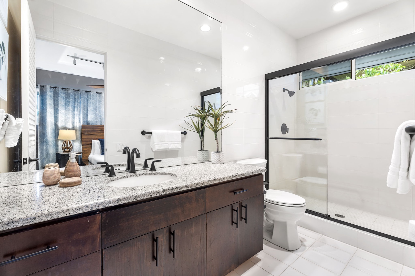Kailua Kona Vacation Rentals, Hale Nai'a - Pamper yourself in this modern bathroom featuring granite countertops, elegant dark cabinetry, and a pristine walk-in shower with glass doors.