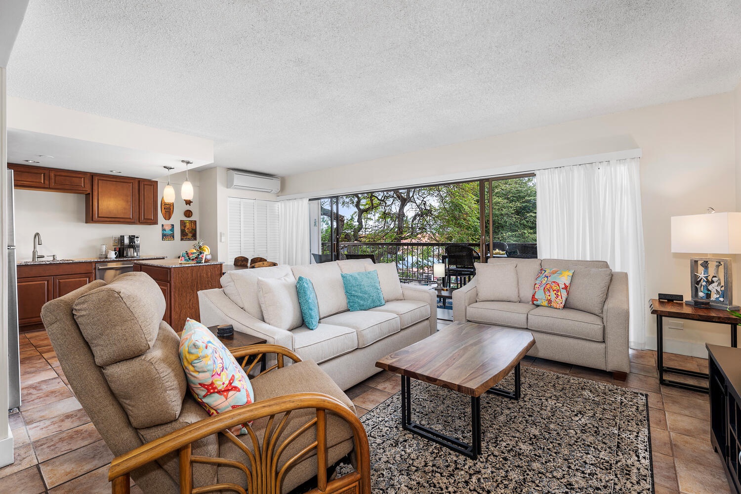 Kailua Kona Vacation Rentals, Kona Plaza 201 - Relax in your spacious living area with comfortable seating, modern kitchen, and lanai overlooking lush greenery.