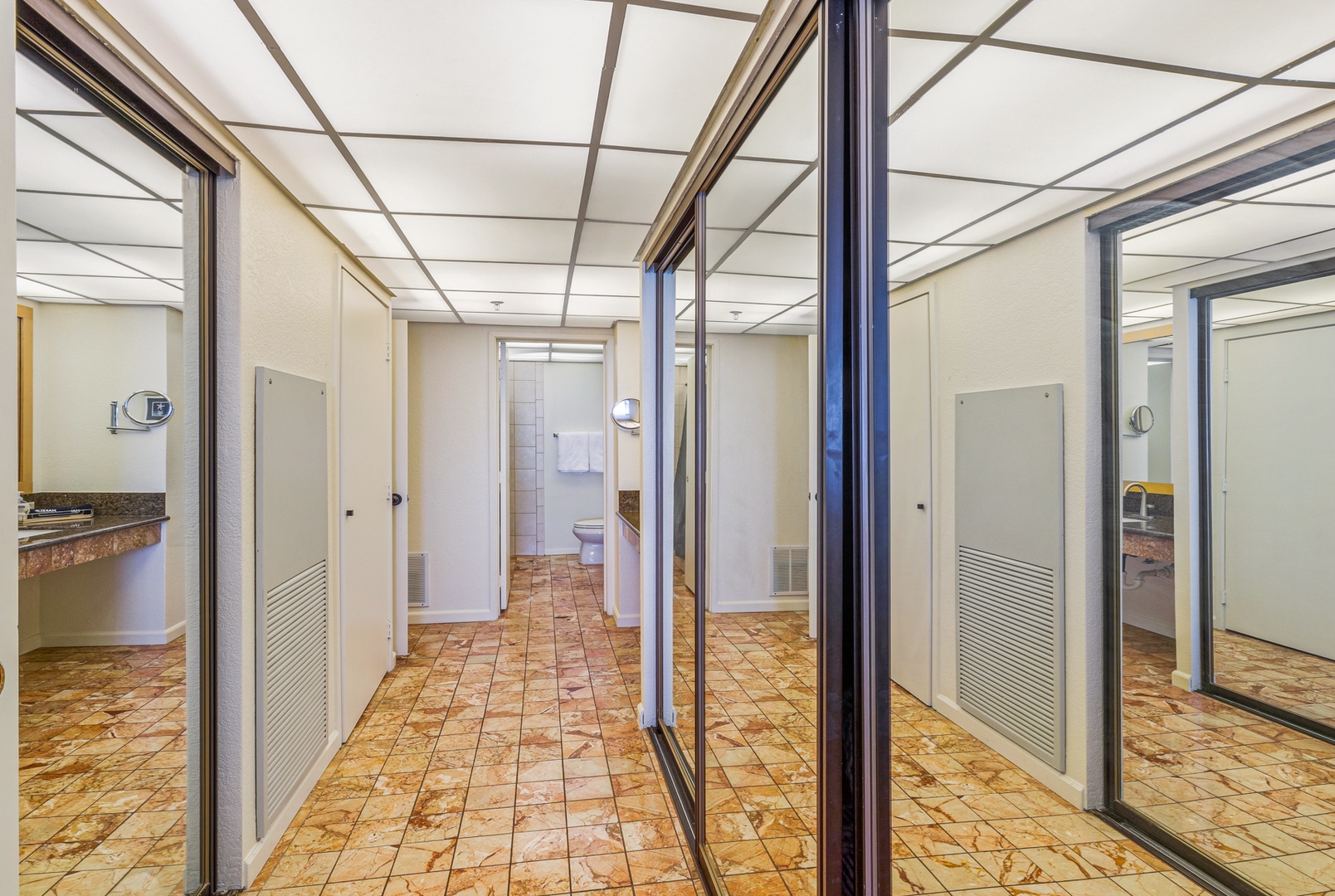 Lahaina Vacation Rentals, Kaanapali Shores 502 - This hallway features mirrored closet doors and tiled flooring, creating an airy feel while leading to the bathroom. The ample closet space offers convenient storage options.