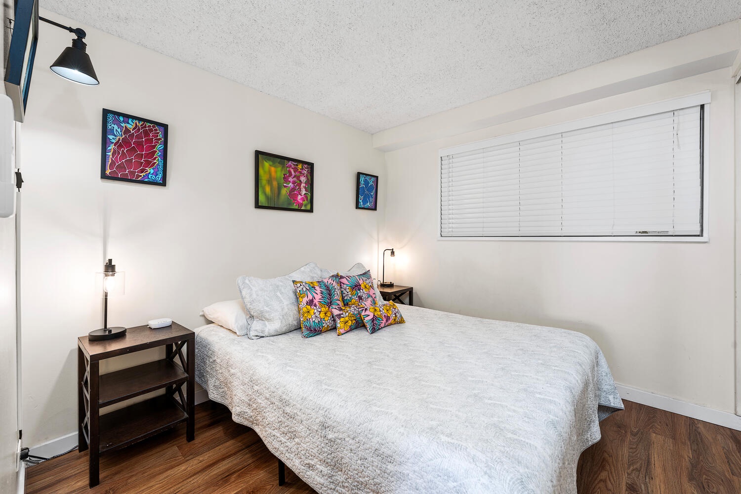 Kailua Kona Vacation Rentals, Kona Plaza 201 - Unwind in your bright bedroom featuring vibrant artwork, cozy reading lamps, and soft linens—your perfect retreat after exploring the city.