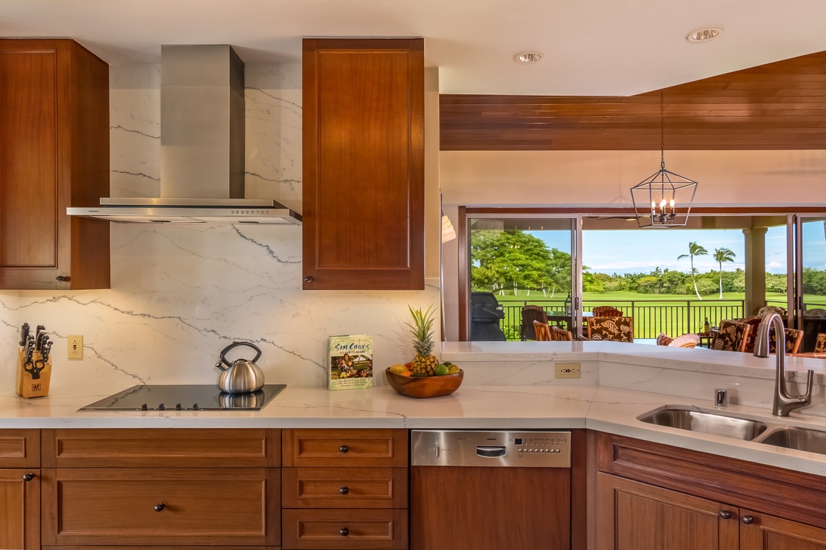 Kailua Kona Vacation Rentals, Fairways Villa 120A - Cook with stunning golf course views through expansive windows in this elegant kitchen featuring warm wood cabinetry and marble countertops.