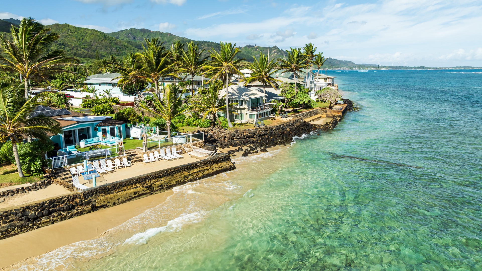 Hauula Vacation Rentals, Private Beach Paradise - Beachfront home set along turquoise waters with a lush mountain backdrop and swaying palms.