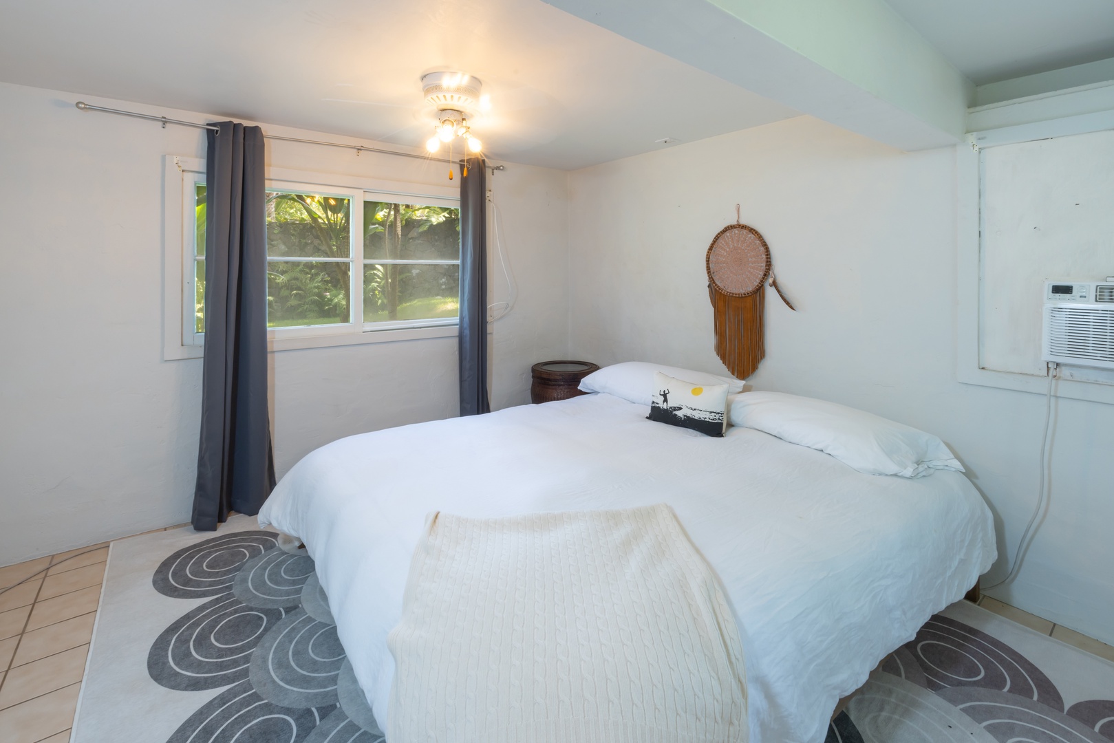 Kahuku Vacation Rentals, Hale Pellicano - The guest bedroom has a king-sized bed, window AC and garden view.